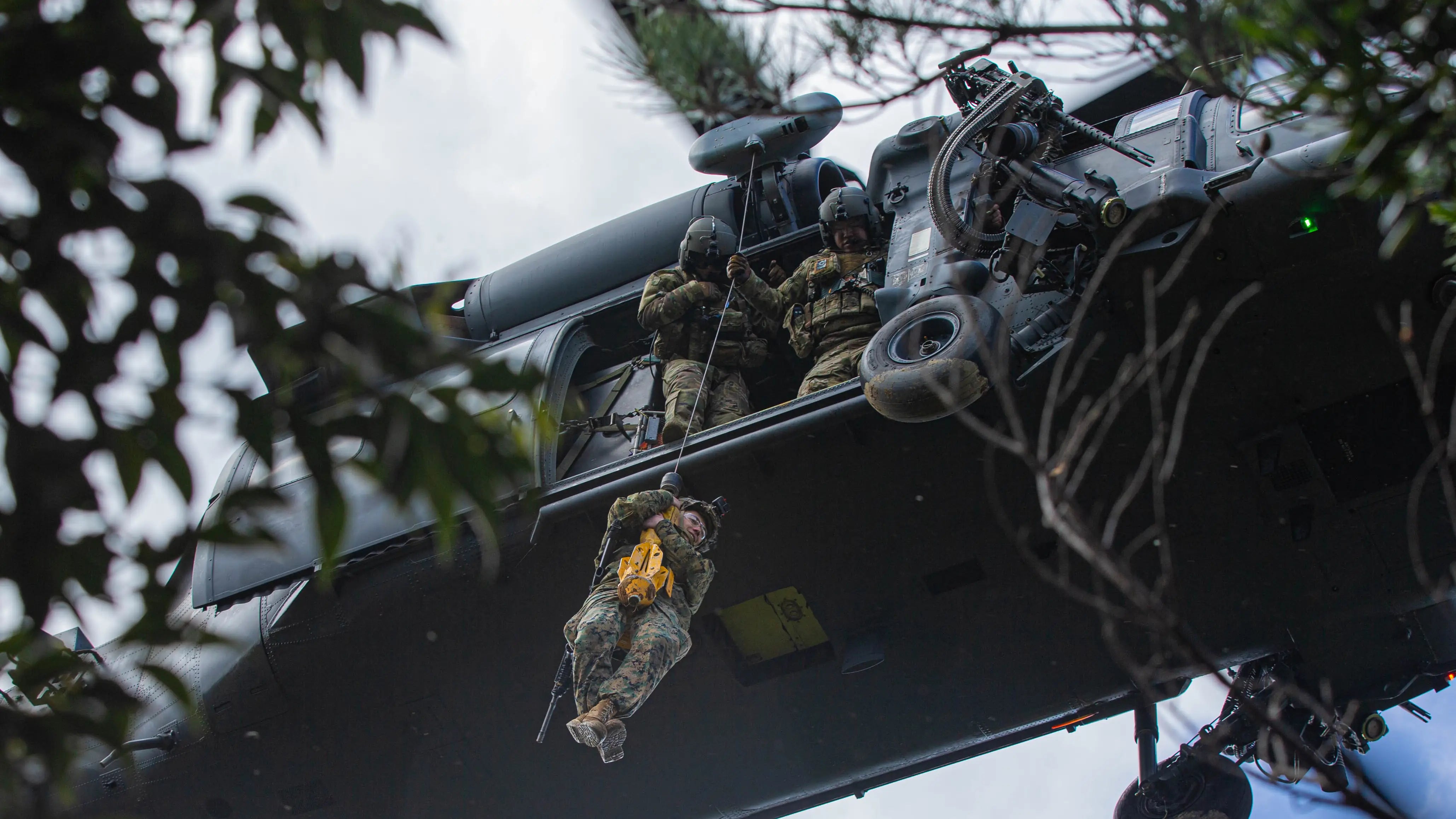 A Marine descending on a line from a helicopter as crew assist from the door, the duty conditions Covert Threads tactical military socks are made for