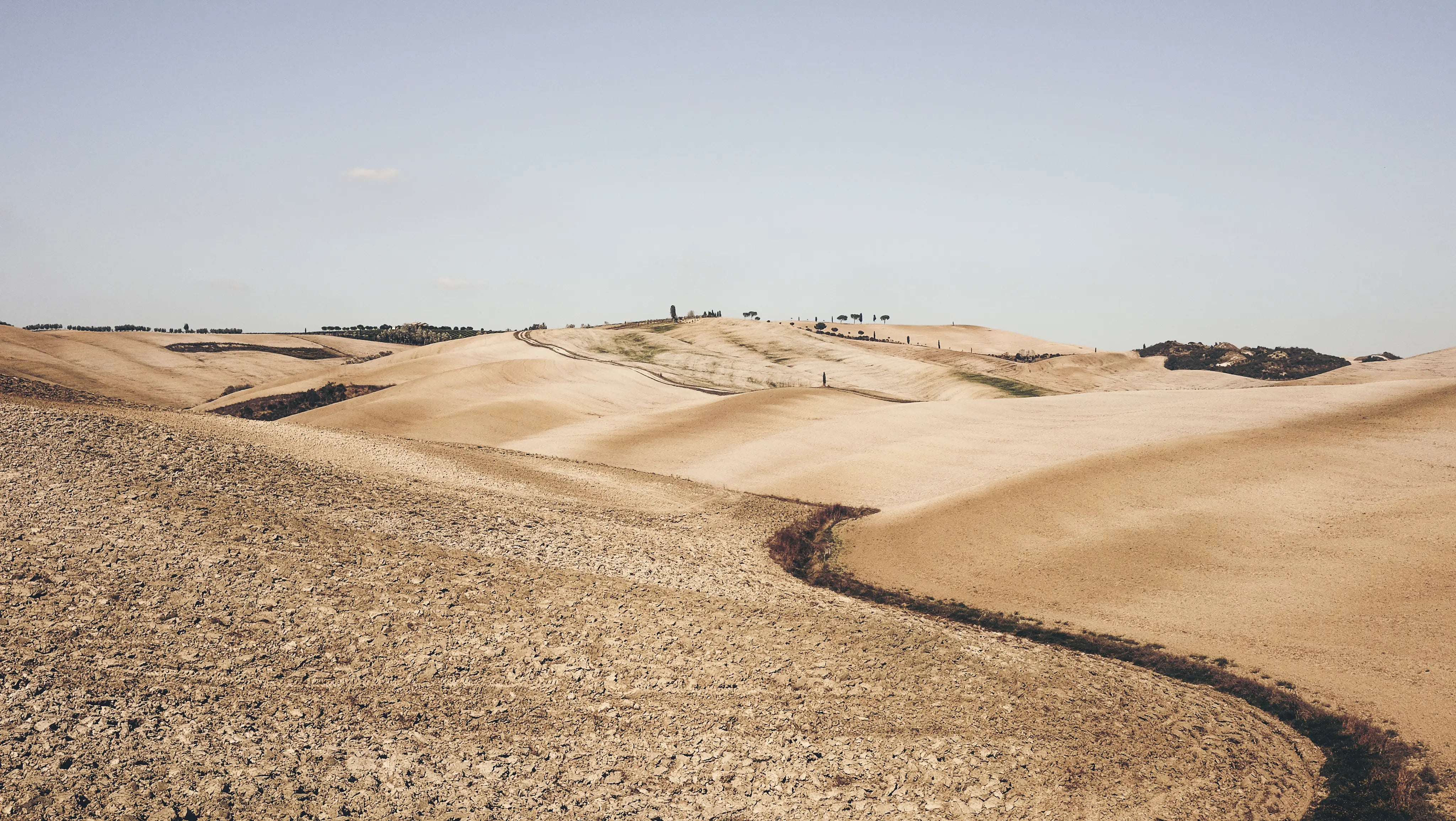 A dry, sun-baked landscape of pale hills and scrub, one of the many kinds of heat Covert Threads hot weather socks are built to handle