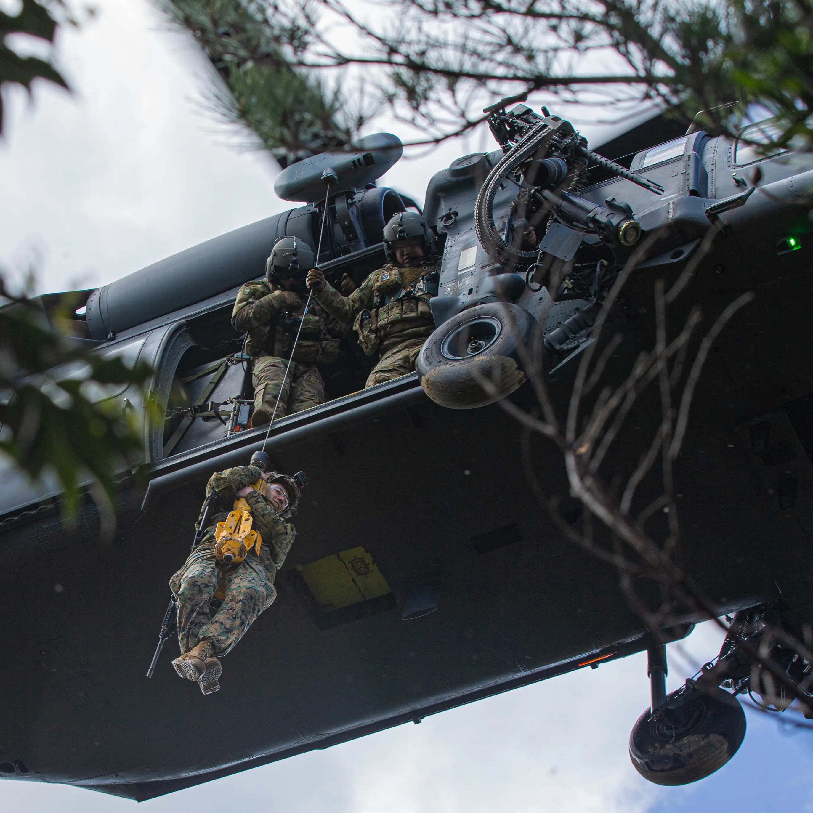 A Marine descending on a line from a helicopter as crew assist from the door, the duty conditions Covert Threads tactical military socks are made for